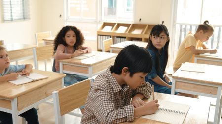 Asian skilled student working on classwork or doing test while sitting at classroom. Diverse...