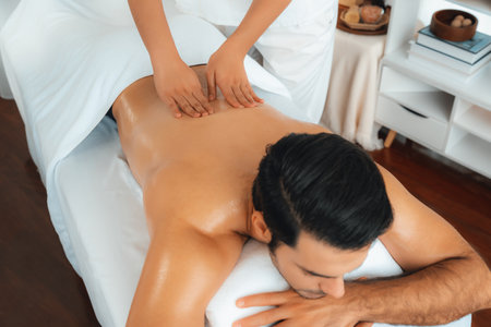 Caucasian man customer enjoying relaxing anti-stress spa massage and pampering with beauty skin recreation leisure in day light ambient salon spa at luxury resort or hotel. Quiescentの写真素材