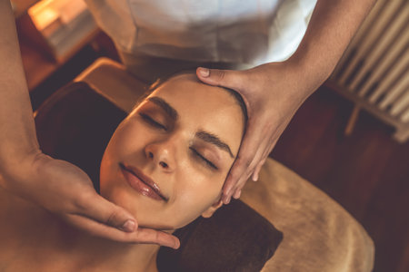 Closeup caucasian woman enjoying relaxing anti-stress head massage and pampering facial beauty skin recreation leisure in warm candle lighting ambient salon spa in luxury resort or hotel. Quiescentの写真素材