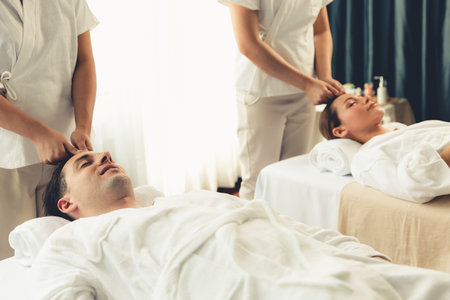 Caucasian couple enjoying relaxing anti-stress head massage and pampering facial beauty skin recreation leisure in dayspa modern light ambient at luxury resort or hotel spa salon. Quiescentの写真素材