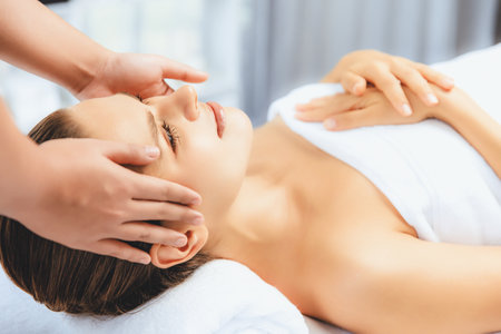 Caucasian woman enjoying relaxing anti-stress head massage and pampering facial beauty skin recreation leisure in dayspa modern light ambient at luxury resort or hotel spa salon. Quiescentの写真素材