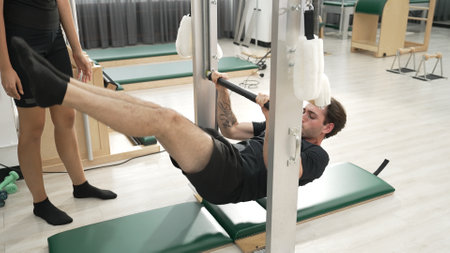 Professional pilates instructor guiding a client during an inversion stretch on a Pilates frame at...