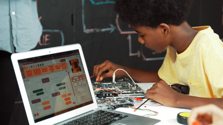 African boy learning to use electronic tool while laptop display code while teacher talking about writing engineering prompt. Children coding program to fixing car model. Edification.の写真素材