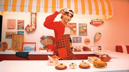 Professional asian restaurant worker prepare food and standing behind food bar. Attractive waiter with red apron picking cherry and throw at camera while looking at camera. Crazy dance. Regalement.のeditorial素材