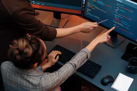Top view of IT developers discussing with point to intelligent website development coder system running data online two screens information technology at neon light room at modern office. Infobahn.の写真素材