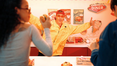 Restaurant coworker with yellow shirt and red cap dancing while service customer. Professional...