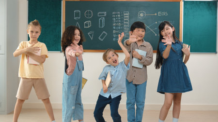 Multicultural elementary student in casual cloth looking at camera while standing at classroom. Group of cute diverse children hold notebook and smiling to camera at blackboard in classroom. Pedagogy.の写真素材