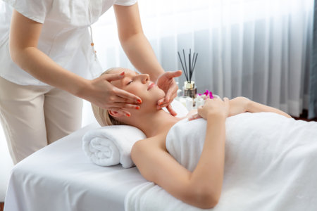 Caucasian woman enjoying relaxing anti-stress head massage and pampering facial beauty skin recreation leisure in dayspa modern light ambient at luxury resort or hotel spa salon. Quiescentの写真素材