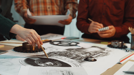A diverse team collaborates on an engineering design, sketching detailed plans and illustrations on a table filled with tools and project papers in a professional workspace. SACTRのeditorial素材