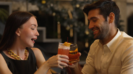 Smiling beautiful woman making a toast with Paloma cocktail to smart couple in Old fashioned savoring tasty enjoy drinking in lively conversation at bar refreshing special nightclub party.の写真素材
