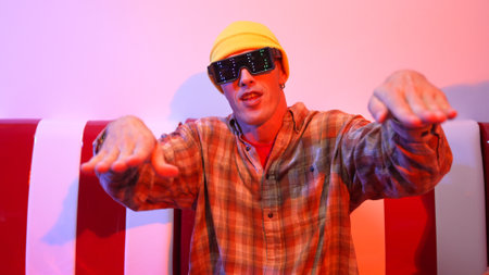 Professional happy dancer with fancy glasses while sitting at house. Close up of energetic man moving to pop or hip hop music while perform freestyle movement. Crazy and funny dancing. Regalement.の写真素材