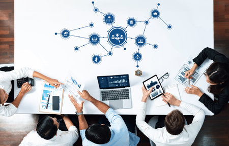 A dynamic business meeting showcasing teamwork and technology integration, with participants reviewing data and charts to drive strategic decisions in a corporate setting.の写真素材