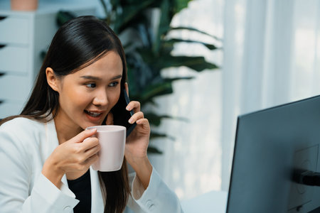 Working young Asian businesswoman calling to customer to present marketing online analysis service while drinking coffee, analyzing on social media website to plan channel sales target. Stratagem.の写真素材