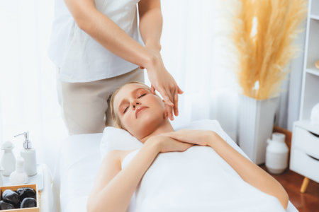 Caucasian woman enjoying relaxing anti-stress head massage and pampering facial beauty skin recreation leisure in dayspa modern light ambient at luxury resort or hotel spa salon. Quiescentの写真素材