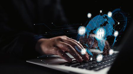 A close-up view of hands typing on a laptop portraying digital networking symbols, illustrating the...
