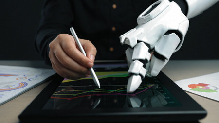 A dynamic scene showing a robotic hand interacting with a tablet, illustrating data analysis through charts and graphs in a contemporary office setup.の写真素材