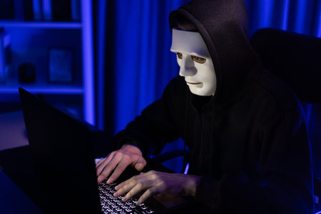 White anonymous mask installing coding password encryption by programming hack, trying to make insecure thorough privacy taking massive database on computer for ransom. Pecuniary.の写真素材