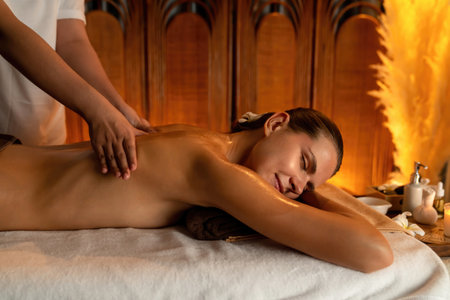 Caucasian woman customer enjoying relaxing anti-stress spa massage and pampering with beauty skin recreation leisure in warm candle lighting ambient salon spa at luxury resort or hotel. Quiescentのeditorial素材