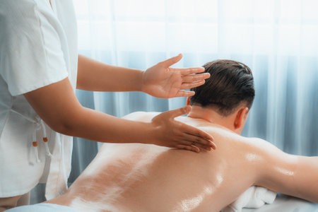 Caucasian man customer enjoying relaxing anti-stress spa massage and pampering with beauty skin recreation leisure in day light ambient salon spa at luxury resort or hotel. Quiescentの写真素材