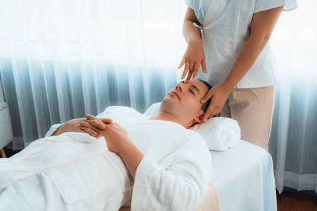Caucasian man enjoying relaxing anti-stress head massage and pampering facial beauty skin recreation leisure in dayspa modern light ambient at luxury resort or hotel spa salon. Quiescentの写真素材