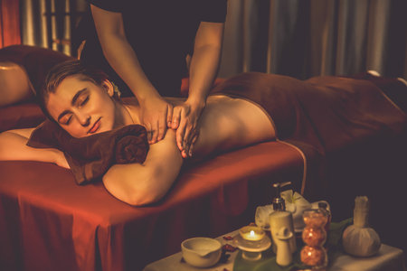 Caucasian couple customer enjoying relaxing anti-stress spa massage and pampering with beauty skin recreation leisure in warm candle lighting ambient salon spa at luxury resort or hotel. Quiescentの写真素材