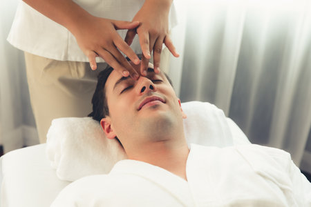 Caucasian man enjoying relaxing anti-stress head massage and pampering facial beauty skin recreation leisure in dayspa modern light ambient at luxury resort or hotel spa salon. Quiescentの写真素材