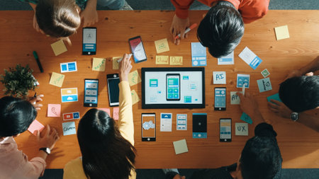 Top view of software developer team looking Ux Ui design for mobile phone interface from tablet...