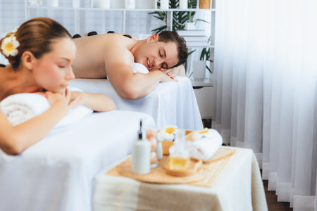 Hot stone massage at spa salon in luxury resort with day light serenity ambient, blissful couple customer enjoying spa basalt stone massage glide over body with soothing warmth. Quiescentの写真素材