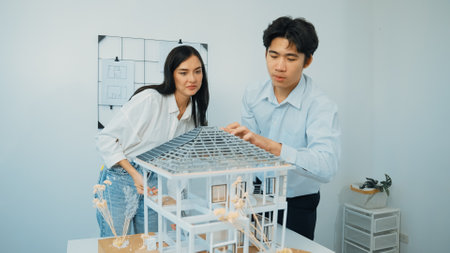 Closeup of young professional skilled architect engineer team focusing on checking the house model structure at modern office. Creative professional design and teamwork concept. Immaculate.の写真素材