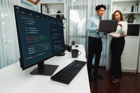 Running on coding programming intelligence system on computer screen with blurry IT developers standing with laptop at corner modern office, talking online software development information. Infobahn.の写真素材