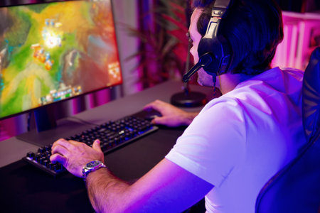Wearing headphones in smart streaming gamer focusing to play Moba online game with players on pc...