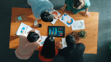 Top down aerial view of smart business people analyze data together at meeting. Group of business team working together and looking at financial chart at tablet placed on meeting table. Convocation.の写真素材