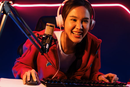 Host channel of smiling beautiful Asian girl streamer playing online game wearing headphone talking...