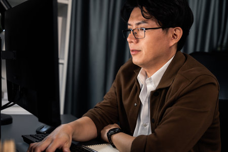 Businessman in casual attire focusing on computer to create business plan report over late night time at office, working on searching tools market planning with new startup company project.の写真素材