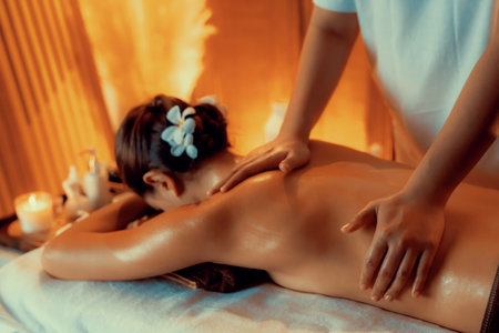 Caucasian woman customer enjoying relaxing anti-stress spa massage and pampering with beauty skin recreation leisure in warm candle lighting ambient salon spa at luxury resort or hotel. Quiescentの写真素材