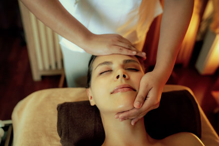 Caucasian woman enjoying relaxing anti-stress head massage and pampering facial beauty skin recreation leisure in warm candle lighting ambient salon spa in luxury resort or hotel. Quiescentの写真素材