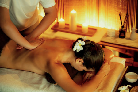 Caucasian woman customer enjoying relaxing anti-stress spa massage and pampering with beauty skin recreation leisure in warm candle lighting ambient salon spa at luxury resort or hotel. Quiescentの写真素材