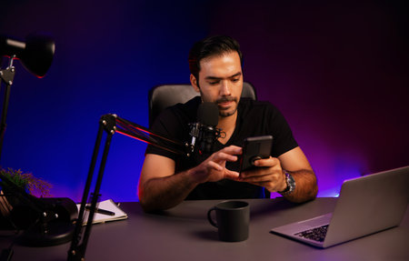 Broadcaster talking to listener on live streaming online, checking message from smartphone on social...