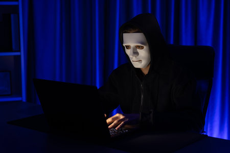 White anonymous mask installing coding password encryption by programming hack, trying to make insecure thorough privacy taking massive database on computer for ransom. Pecuniary.の写真素材