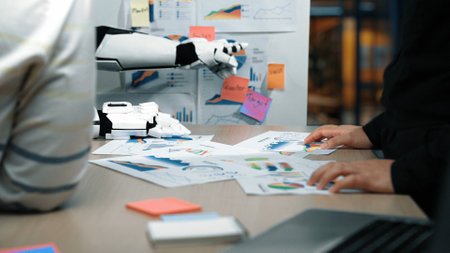 A modern office environment featuring a robotic arm engaged in analyzing various business charts and...