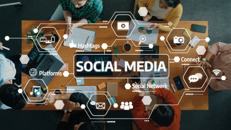 A top-down view of a team collaborating on social media concepts, featuring devices, charts, and engaging discussions in a modern workspace setting.の写真素材