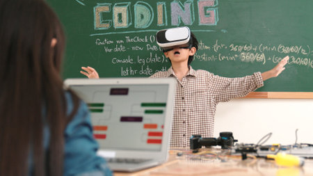 Asian boy wearing VR headset to enter metaworld at table with electronic board while girl coding system. Group of diverse student working together to develop program and writing code. Pedagogy.の写真素材