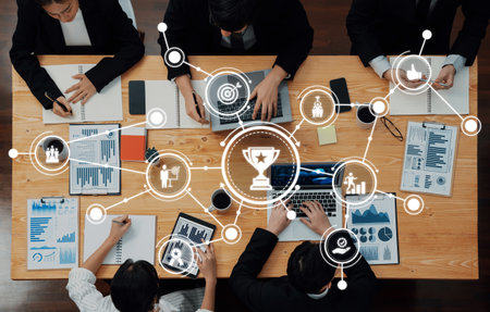 A top view of a dynamic business meeting where diverse professionals collaborate over laptops and...