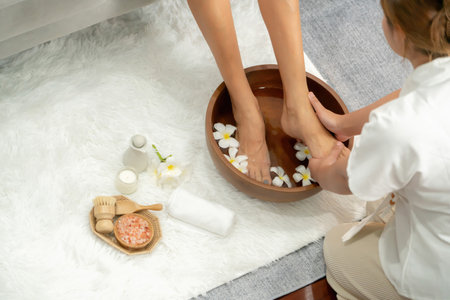 Woman indulges in blissful foot massage at luxurious spa salon while masseur give reflexology therapy in gentle day light ambiance resort or hotel foot spa. Quiescentの写真素材