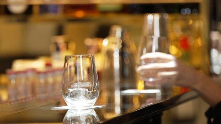 Closeup customer hand with gin fizz or tonic soda at luxurious bar side view in atmosphere at bokeh lighting warm nightclub. Lifestyle at night with friends or couple at pub and restaurant.の写真素材