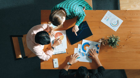 Top view of smart project manager holding document to presenting financial graph to investor while looking at tablet display stock market statistic placed and planning strategy.の写真素材