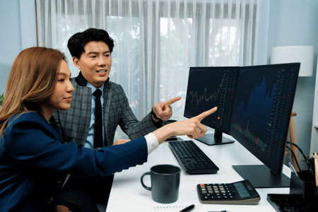 Asian business partners pointing to profit highest dynamic stock exchange data on computer screen...