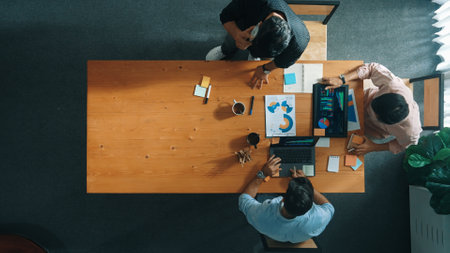 Top view of business team looking at laptop while giving high five and clinking glass to celebrate successful project or increasing sales. Represented unity, teamwork, togetherness.の写真素材