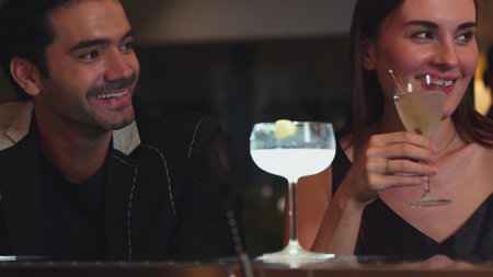Smart couple making a toast with cocktail cheers in martini with olive and margarita savoring tasty...