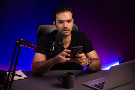 Broadcaster talking to listener on live streaming online, checking message from smartphone on social...